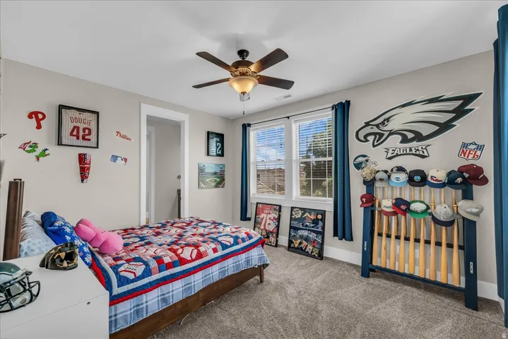Carpeted room with a ceiling fan, dual windows with blinds, a white door frame, and light gray walls