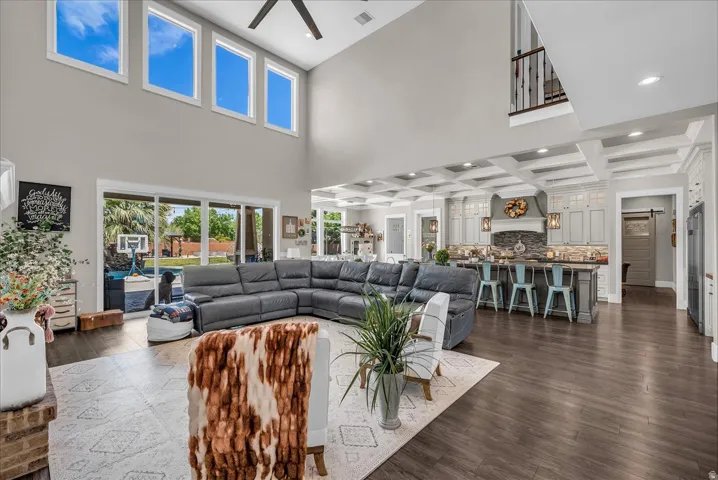 Two-story living area featuring a vaulted ceiling with a fan, wood-finish flooring, and multiple high windows