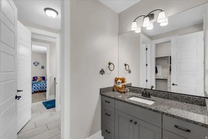 Bathroom vanity featuring a speckled countertop, undermount sink, and dark-finish faucet