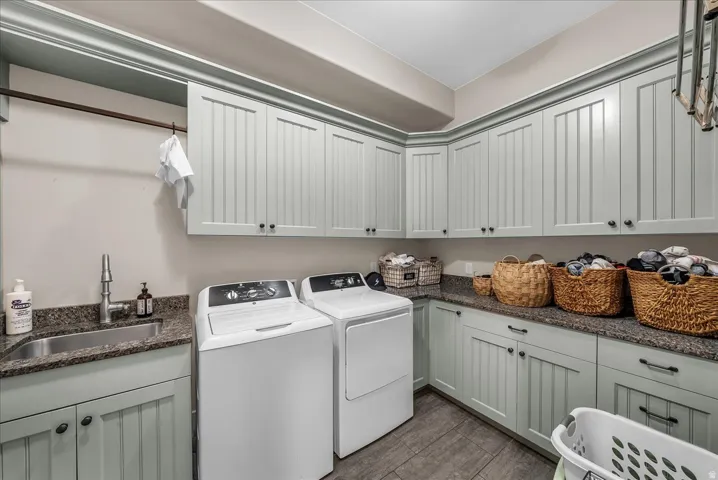 Laundry room featuring beadboard cabinetry, granite-finish countertops, an integrated sink, and an overhead clothes rod