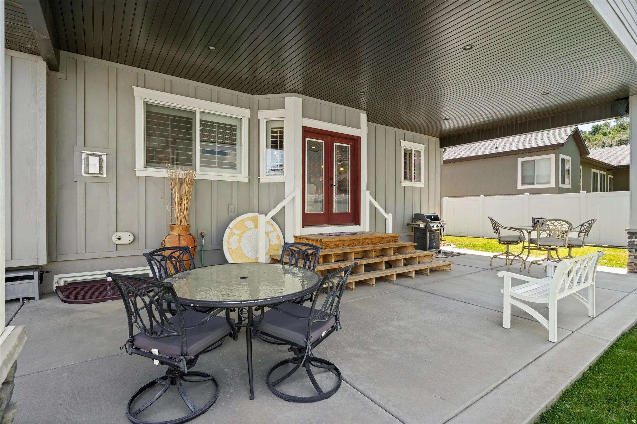 Expansive covered patio featuring a concrete surface, a wood-finish ceiling, and direct access to the interior via double red doors with glass inserts