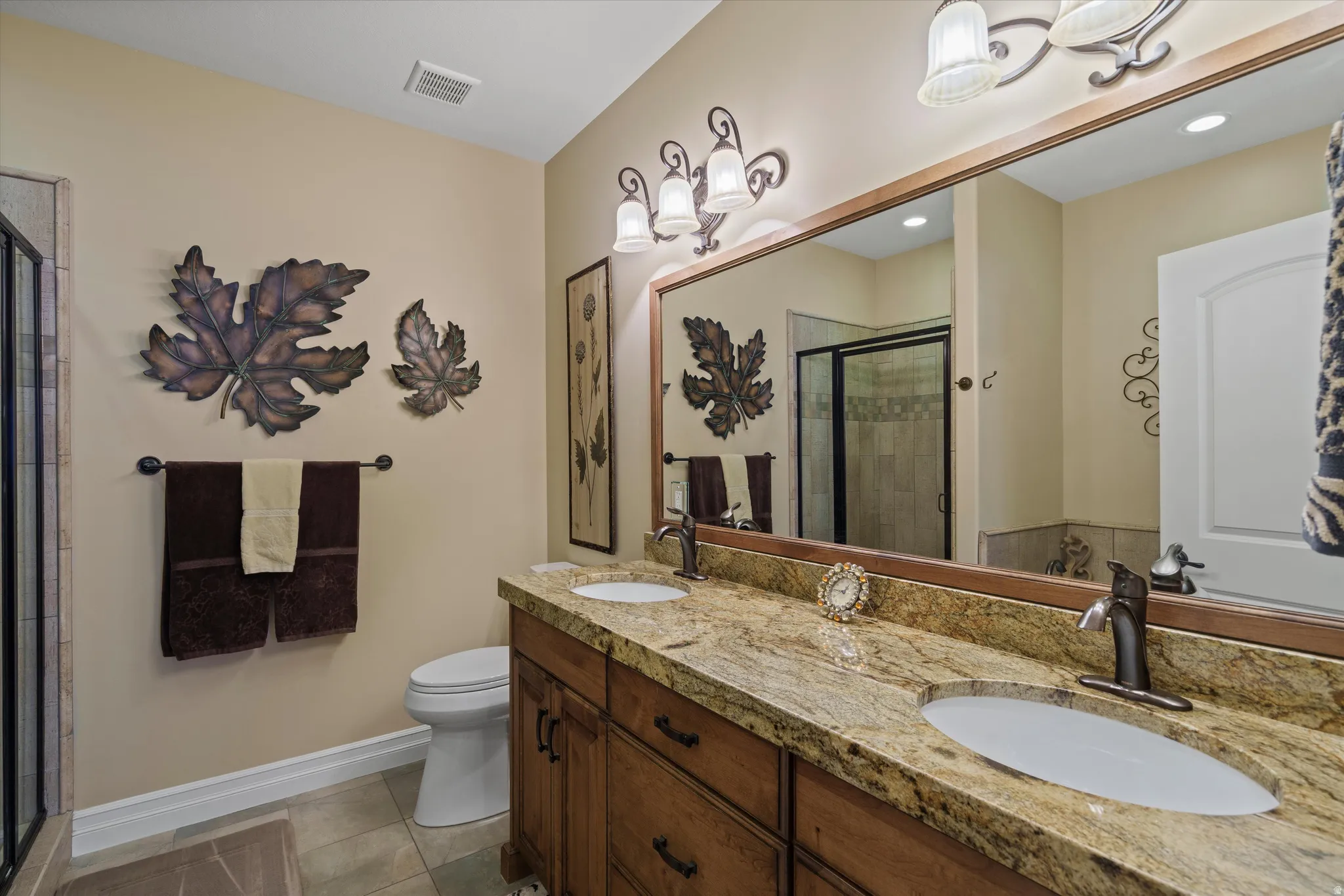 Bathroom vanity with dual undermount sinks, granite countertop, and wood-finish cabinetry