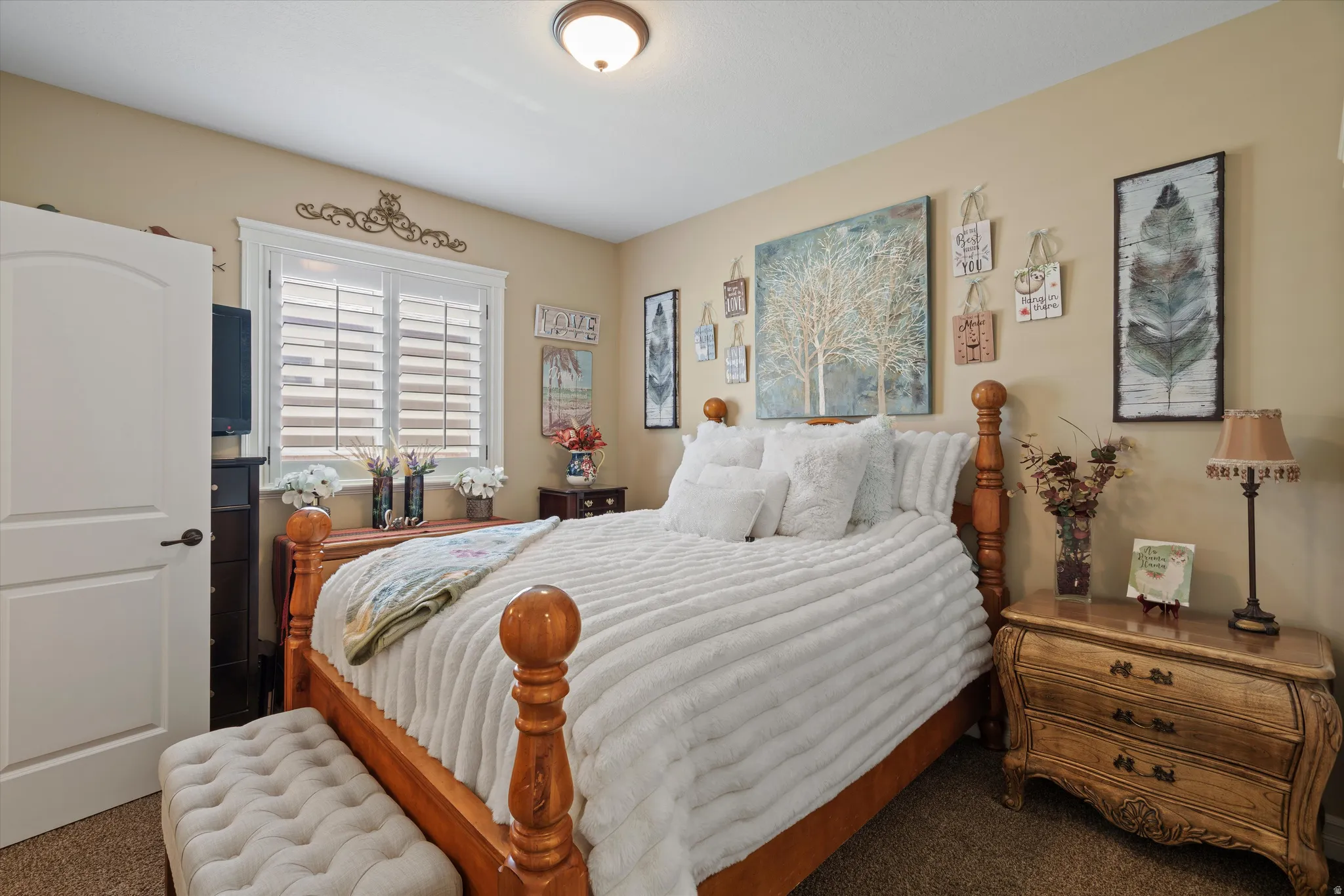Carpeted room featuring a white interior door with an arched panel, a window with plantation shutters and decorative trim, neutral wall paint, and a flush-mount ceiling light fixture