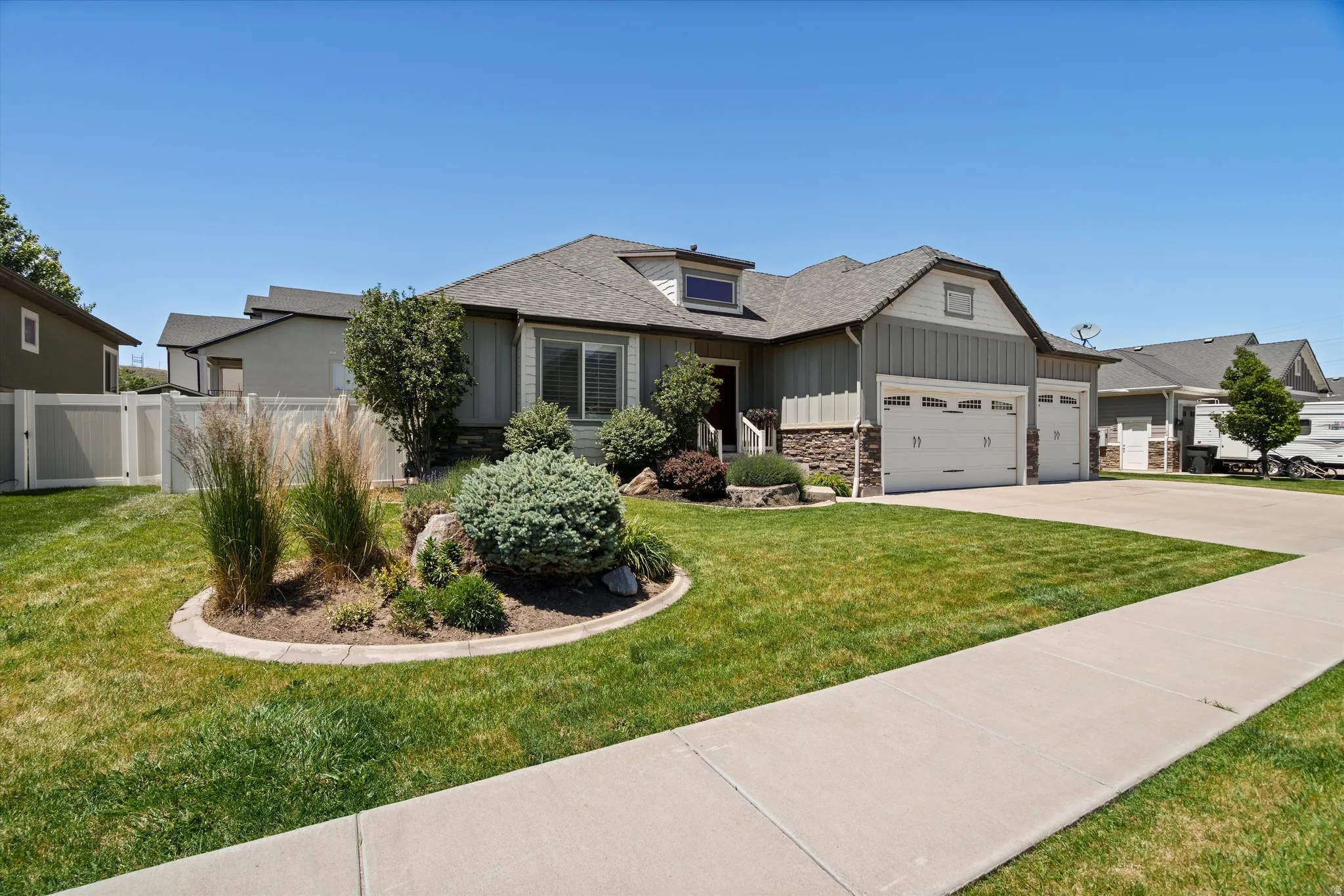Craftsman-style home featuring vertical siding, stone accents, and a multi-car garage with white paneled doors