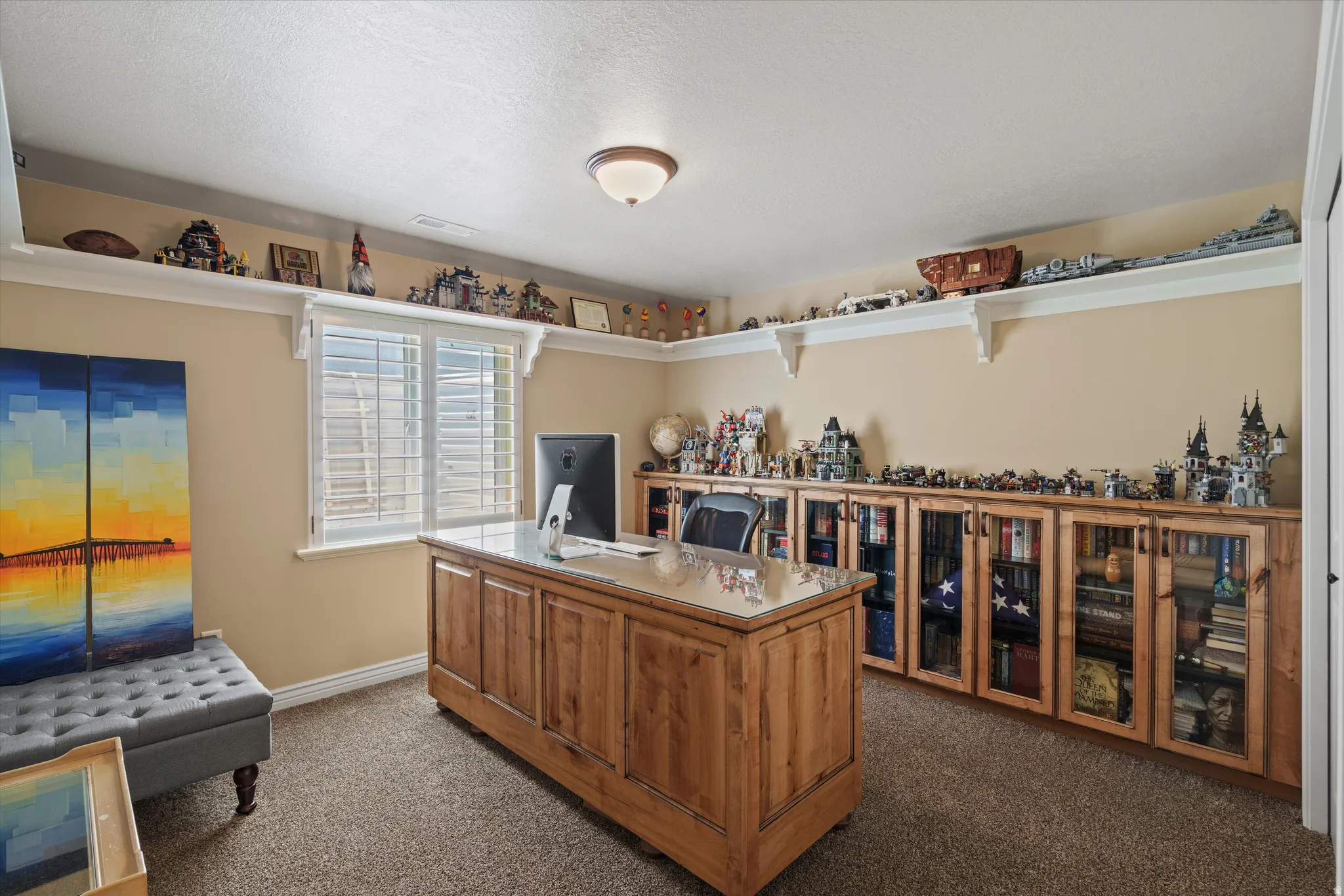 Room featuring extensive built-in cabinetry with glass-front doors, open shelving, and a window with plantation shutters