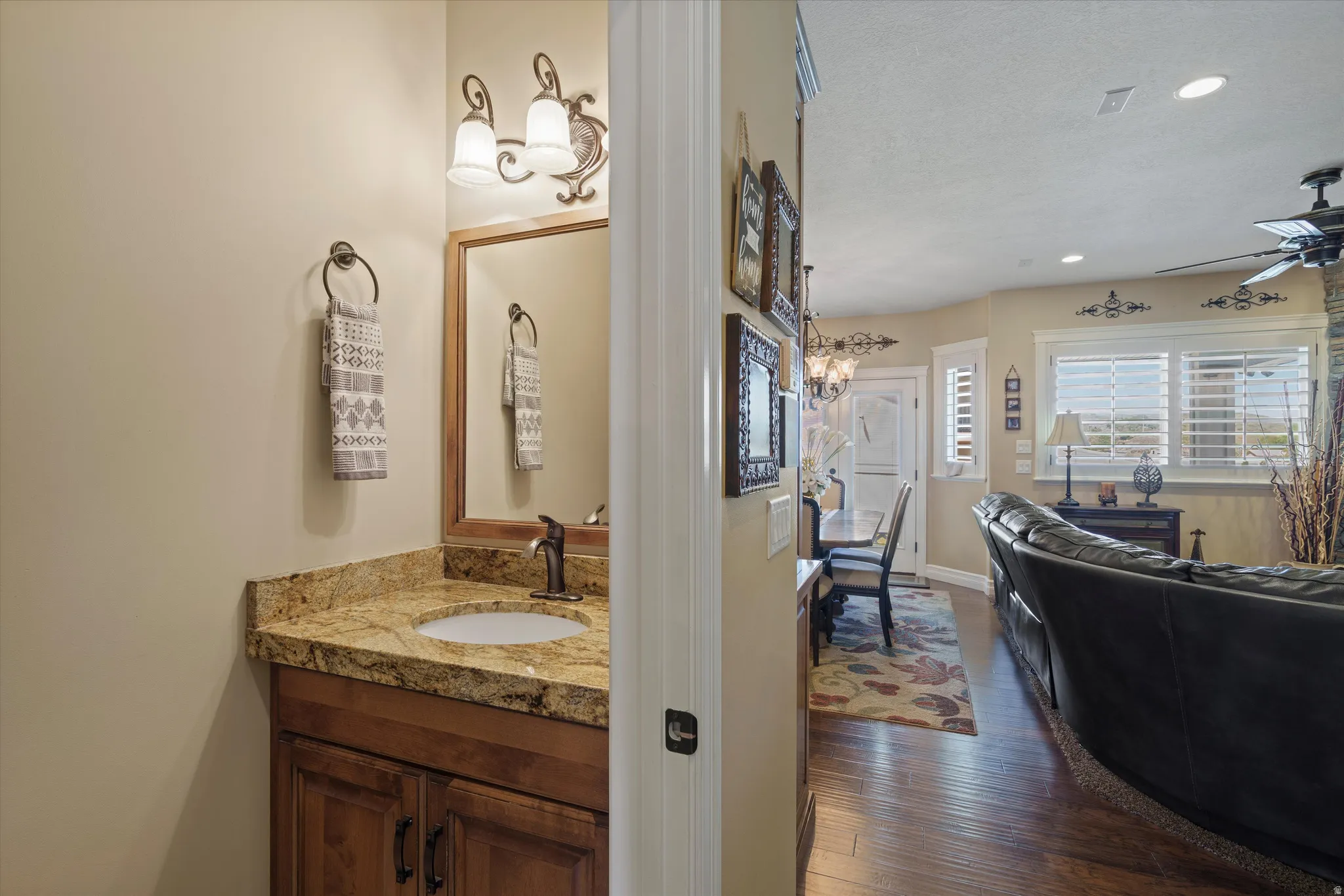 Powder room featuring a wood vanity with a granite countertop, undermount sink, and bronze-finish faucet