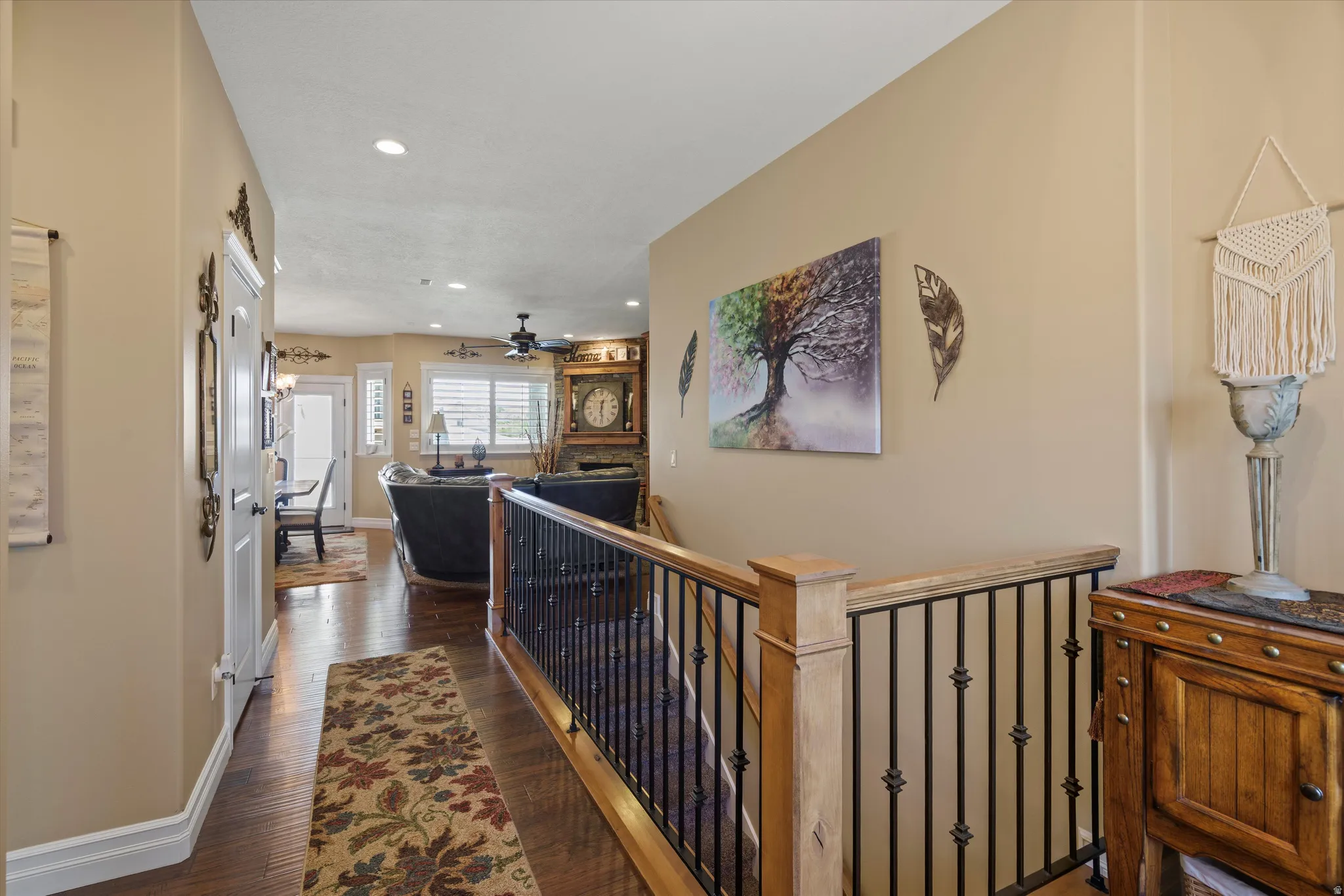 Interior hallway featuring wood-finish flooring, recessed lighting, and a stairway with wood newel posts and black iron balusters