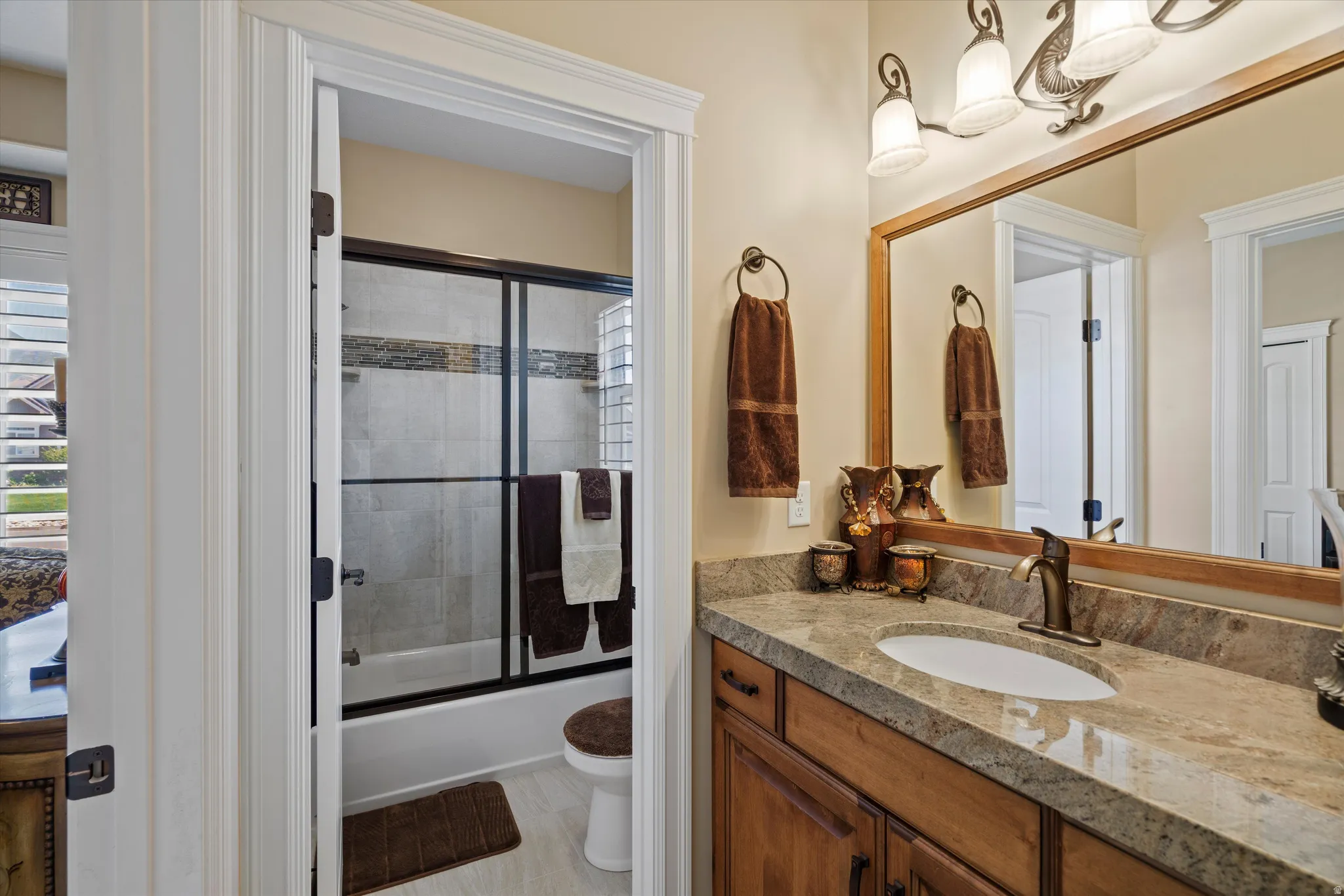 Bathroom featuring a built-in vanity with a stone countertop, an undermount sink, and a framed mirror