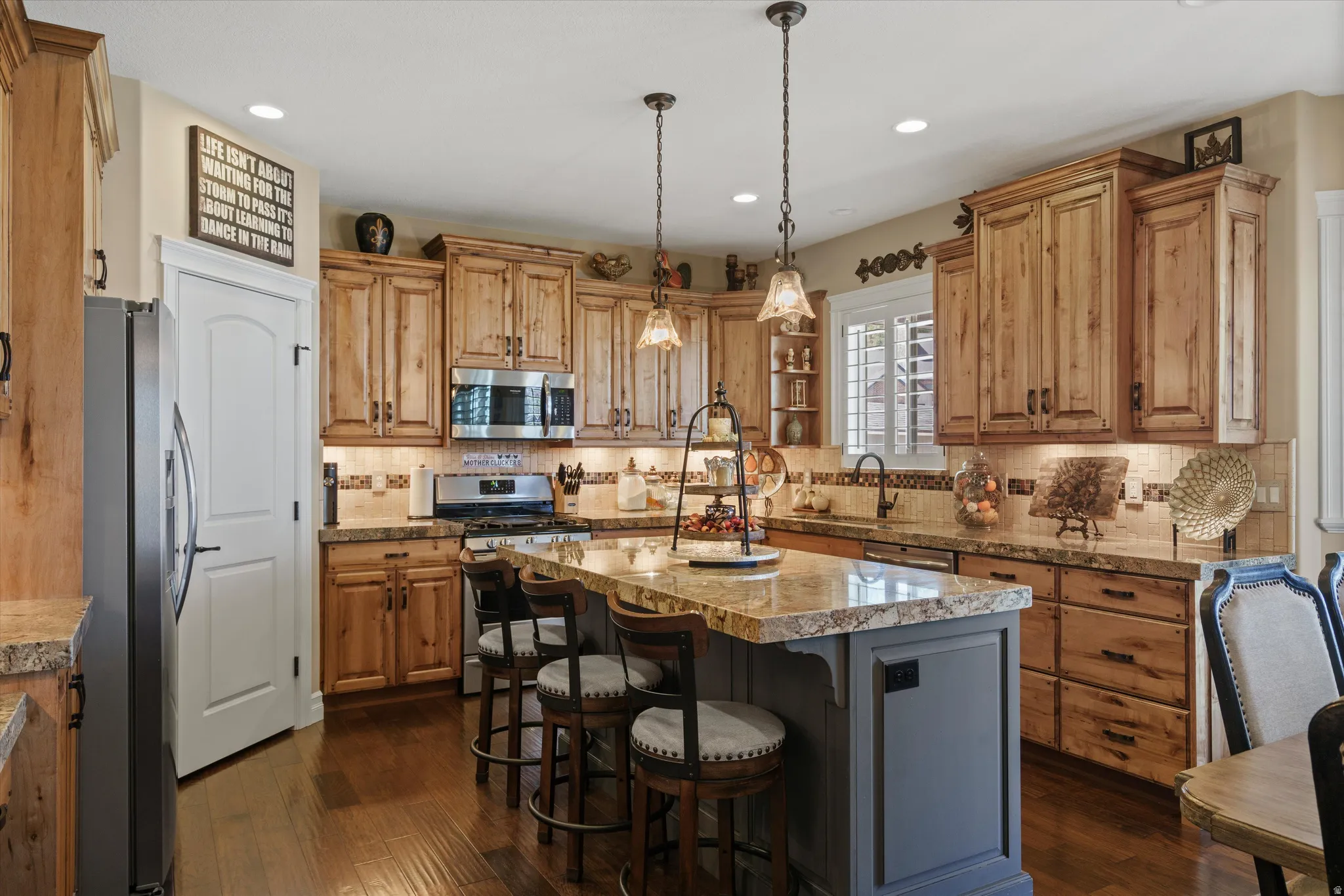 Gourmet kitchen featuring wood-finish cabinetry, stainless steel appliances, and a central island with bar seating