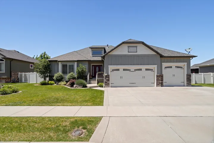 Ranch-style residence featuring a gray exterior with board and batten accents, a dark shingle roof, and a prominent three-car garage