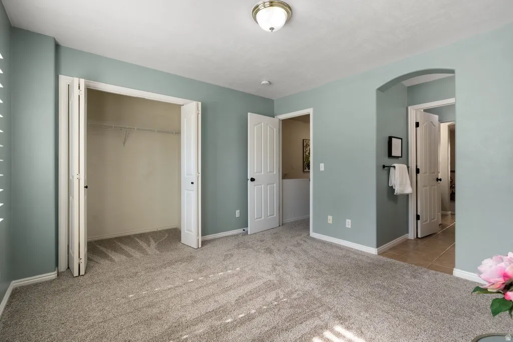 Carpeted interior with light blue walls featuring a bi-fold closet, a ceiling-mounted light fixture, and white baseboards