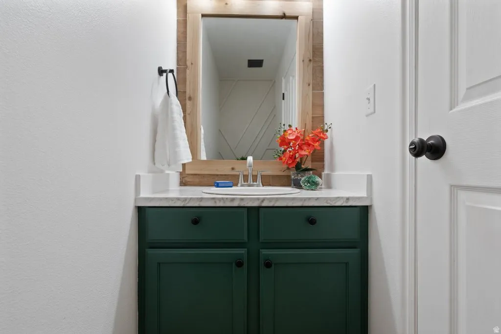 Vanity featuring a dark green cabinet, white countertop, and an undermount sink