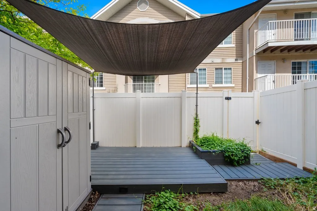 Private patio featuring composite decking, a built-in planter box, and a white privacy fence