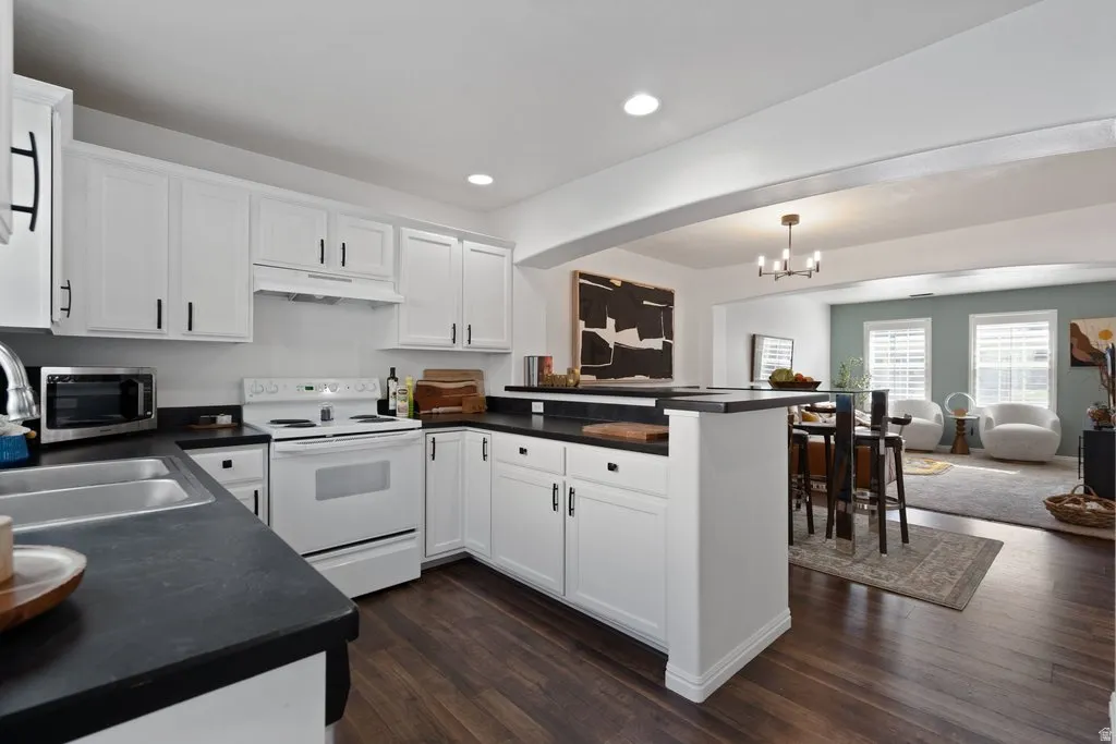 Kitchen featuring white shaker-style cabinetry, dark countertops, and wood-finish flooring