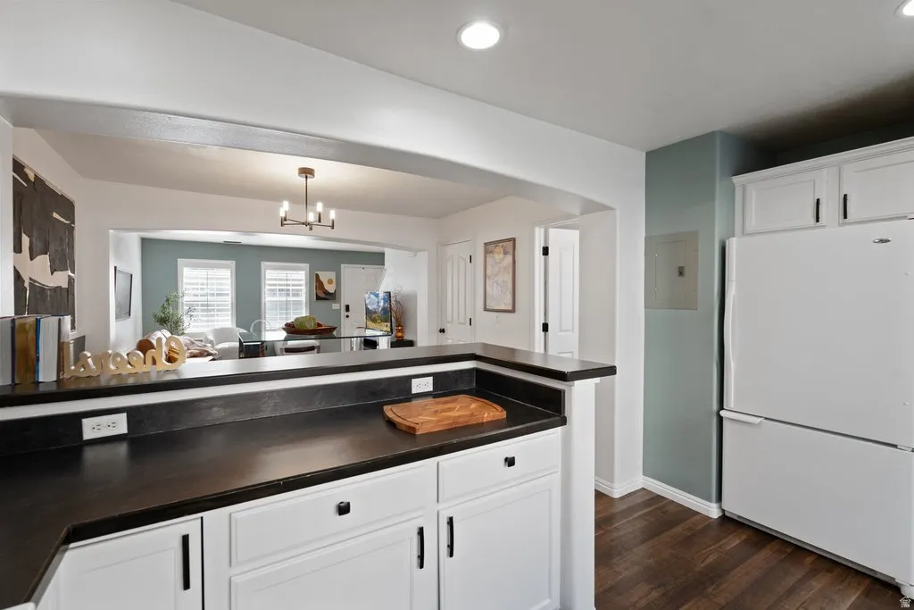 Kitchen featuring white cabinetry, dark countertops, white appliances, and recessed lighting