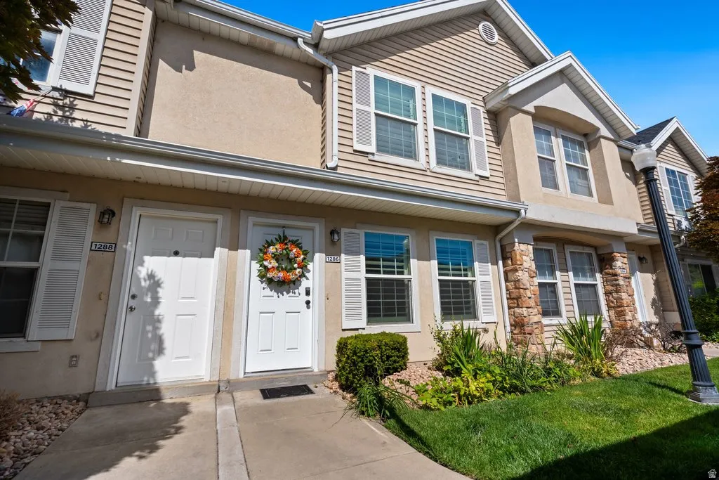 Townhouse exterior featuring dual entry doors, stone facade accents, horizontal siding, and ground-level landscaping