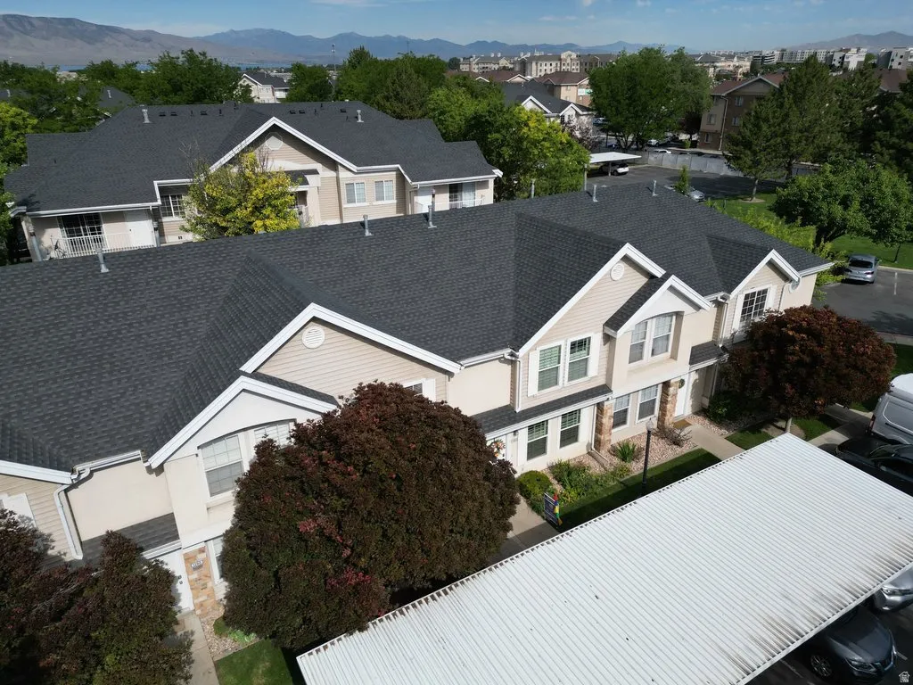 Multi-level townhome exterior featuring light-toned siding, dark shingle roofing, and white trim