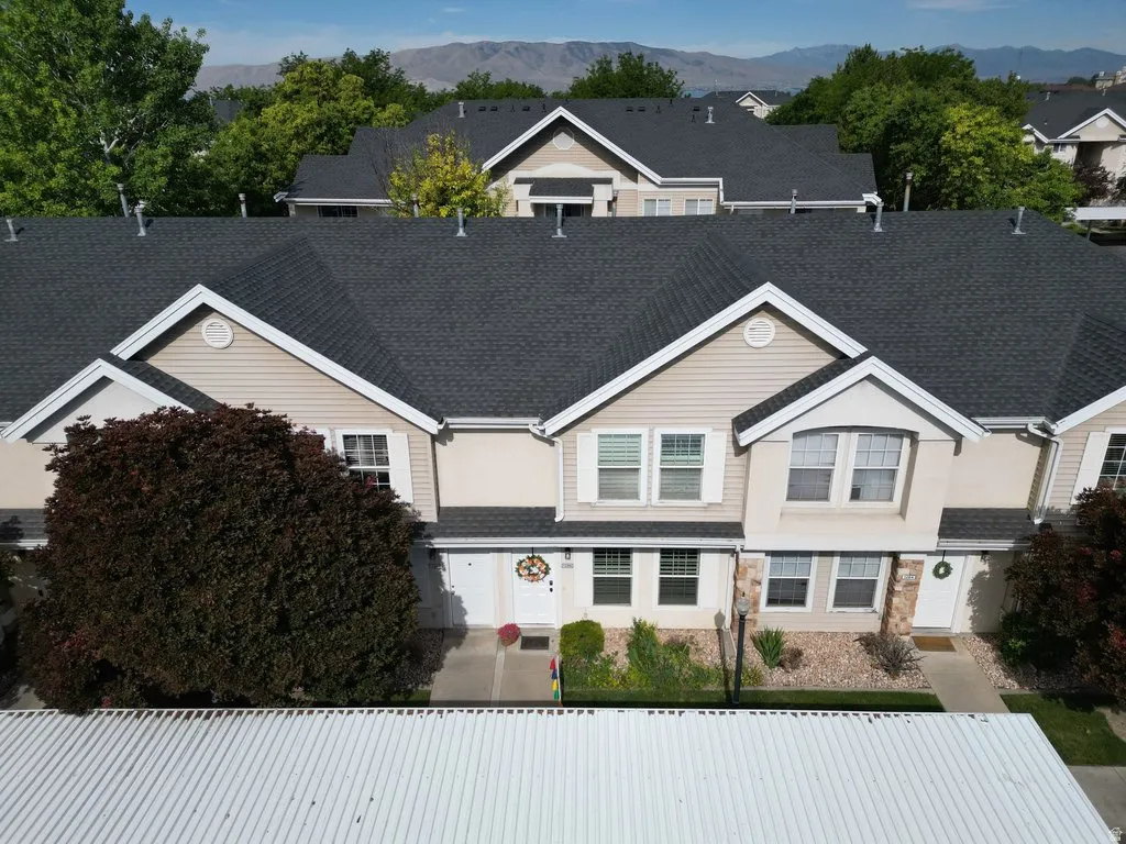 Multi-level townhome exterior featuring light beige siding and stone accents