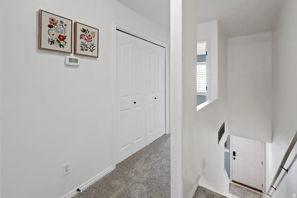 Upper-level hallway with neutral carpeting, white bi-fold closet doors, and light-toned walls