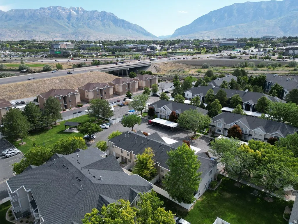 Community of multi-story buildings featuring varied exterior finishes, abundant mature trees, and a common green space with a gazebo