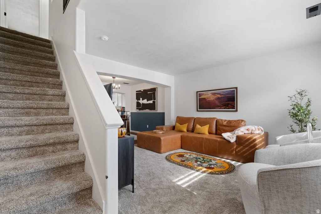 Carpeted staircase with white baluster and handrail, neutral wall paint, and recessed lighting