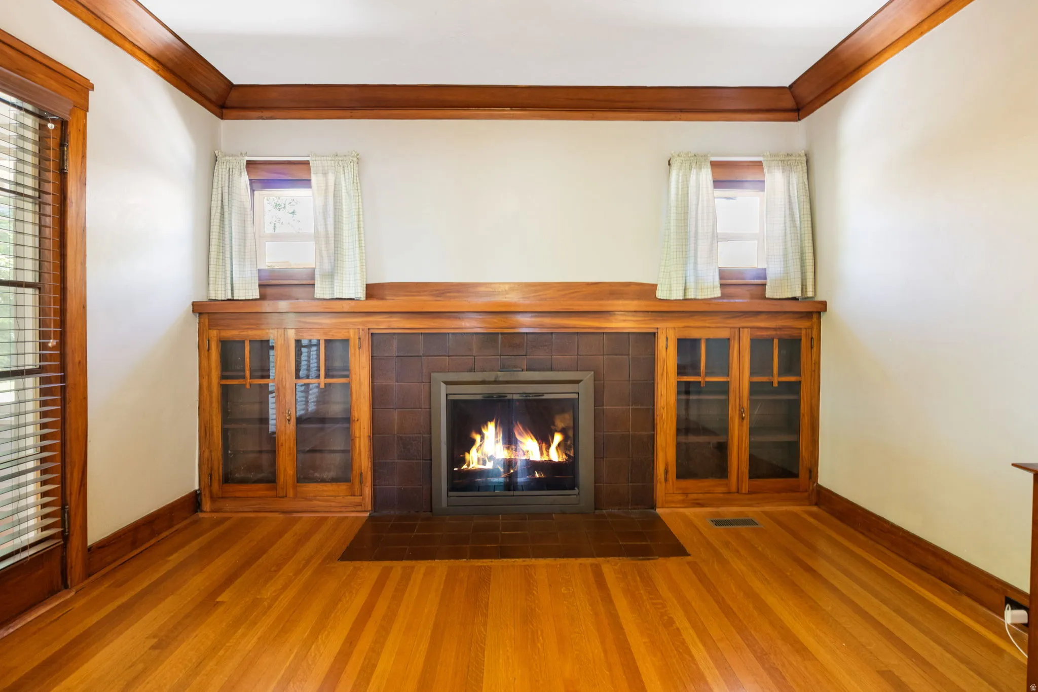 Hardwood flooring throughout the room, complemented by a built-in fireplace with a tile surround and hearth
