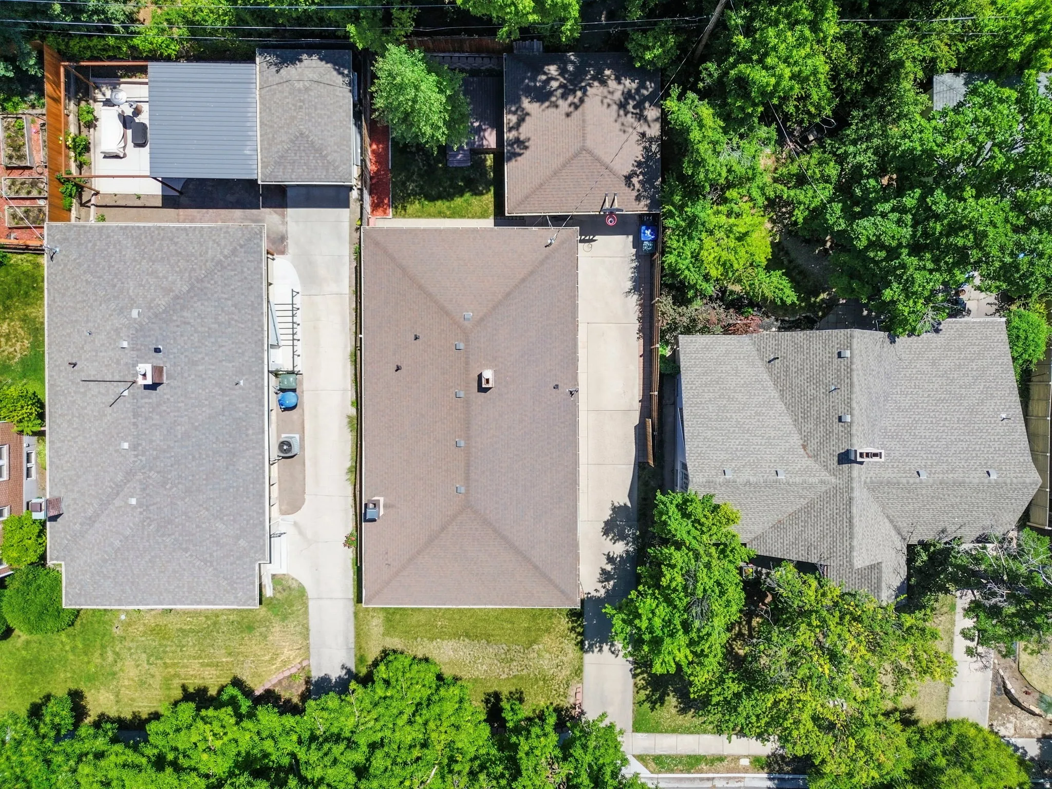 Aerial view highlighting property layout with a brown shingle roof and a concrete driveway