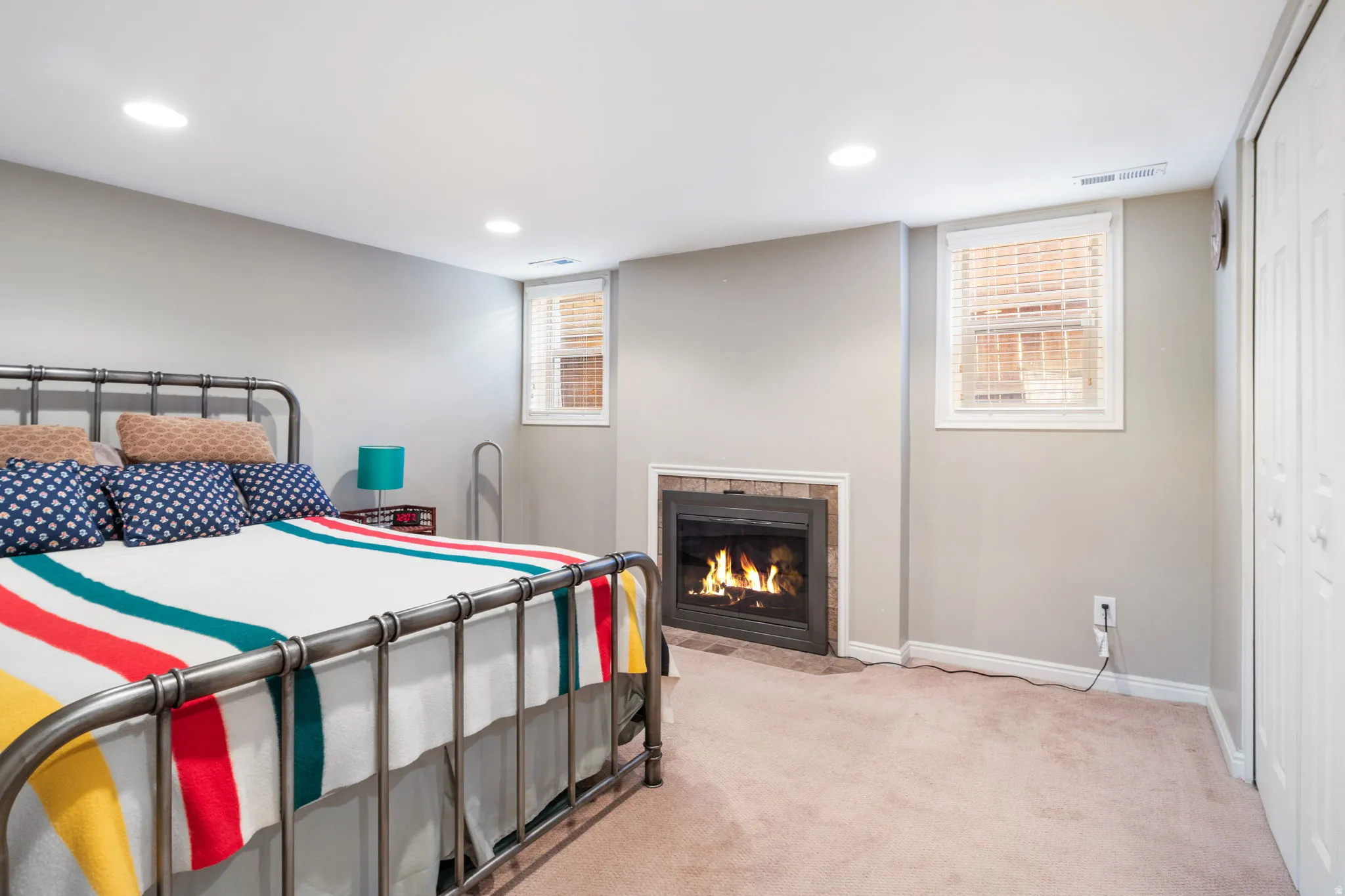 Room featuring a built-in fireplace with a stone surround, recessed lighting, and soft carpet flooring