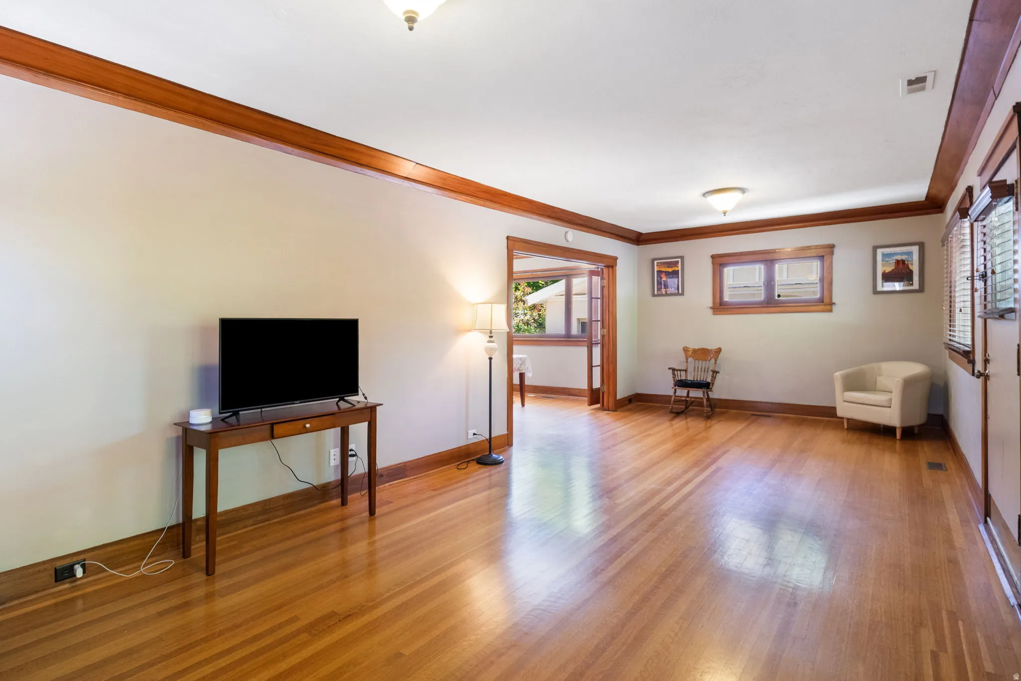Hardwood flooring throughout, framed by dark wood baseboards and crown molding