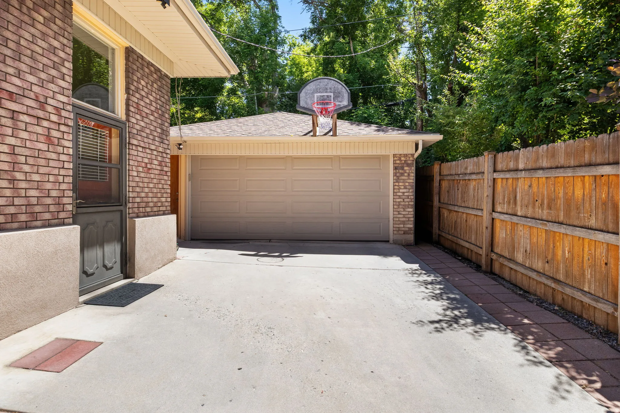 Concrete driveway providing access to a single-car garage featuring a tan overhead door