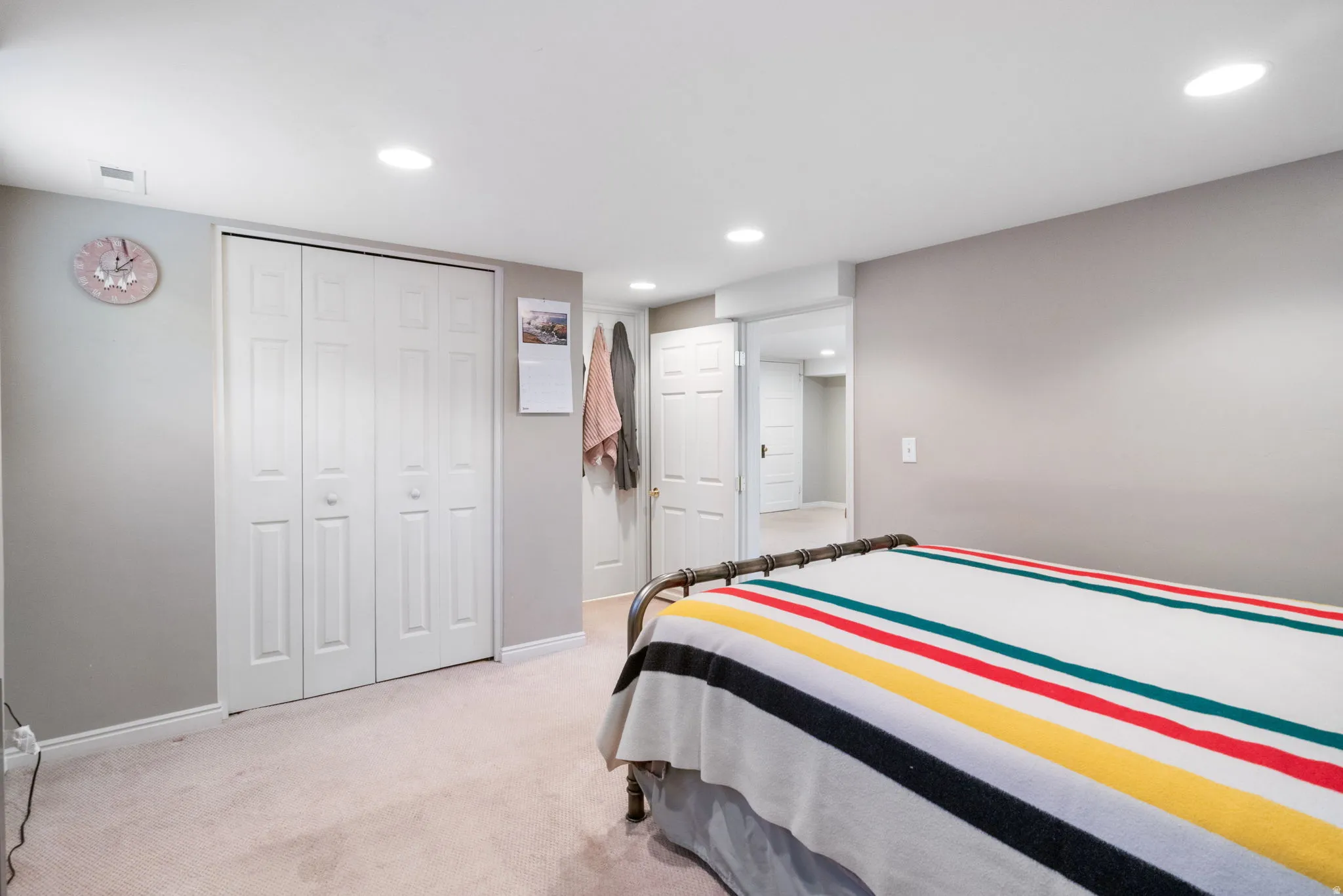 Bedroom featuring soft wall-to-wall carpeting, white bi-fold closet doors, recessed ceiling lighting, and a neutral paint palette