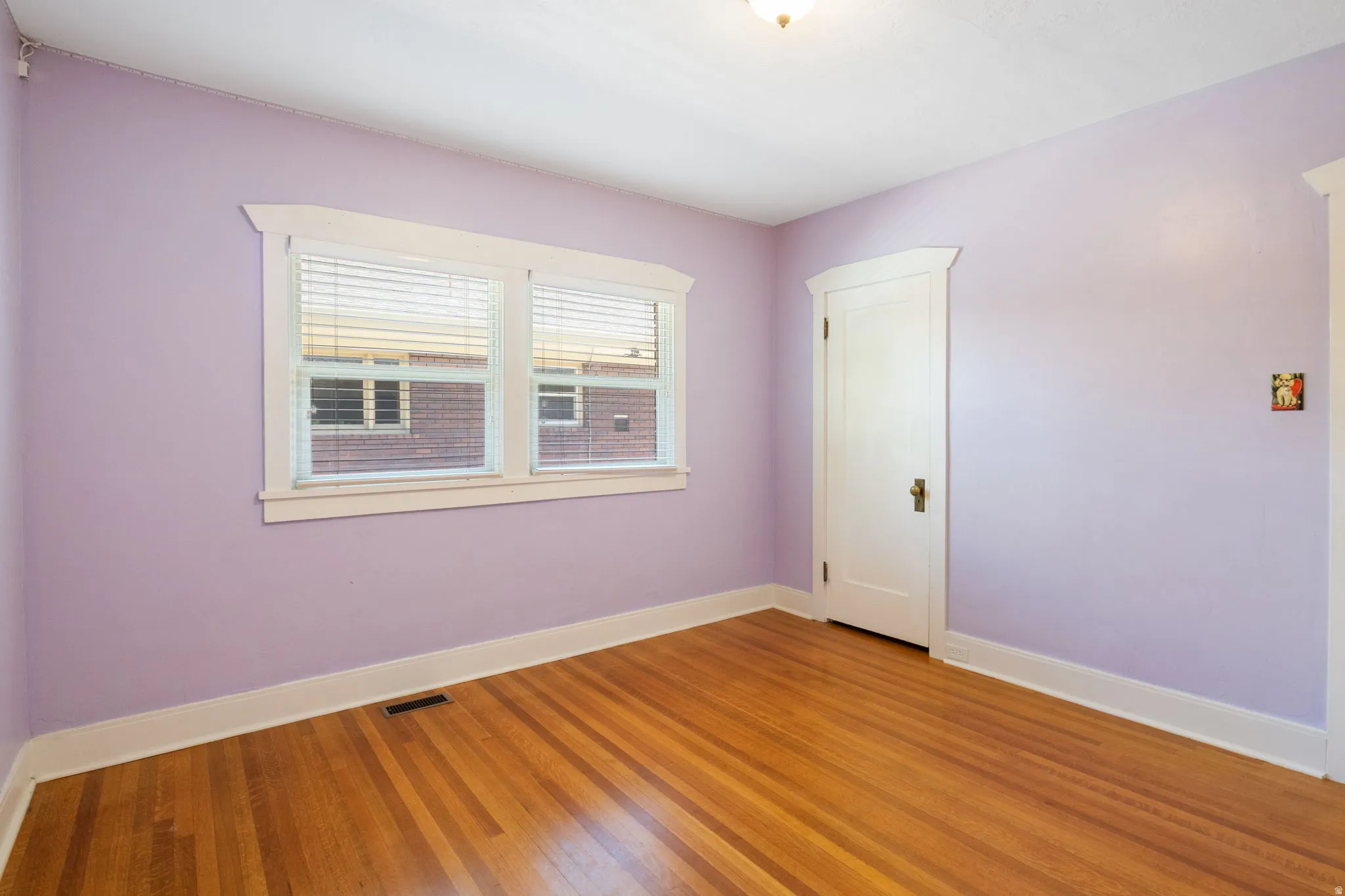 Room featuring light wood-finish flooring, white baseboards, and window trim