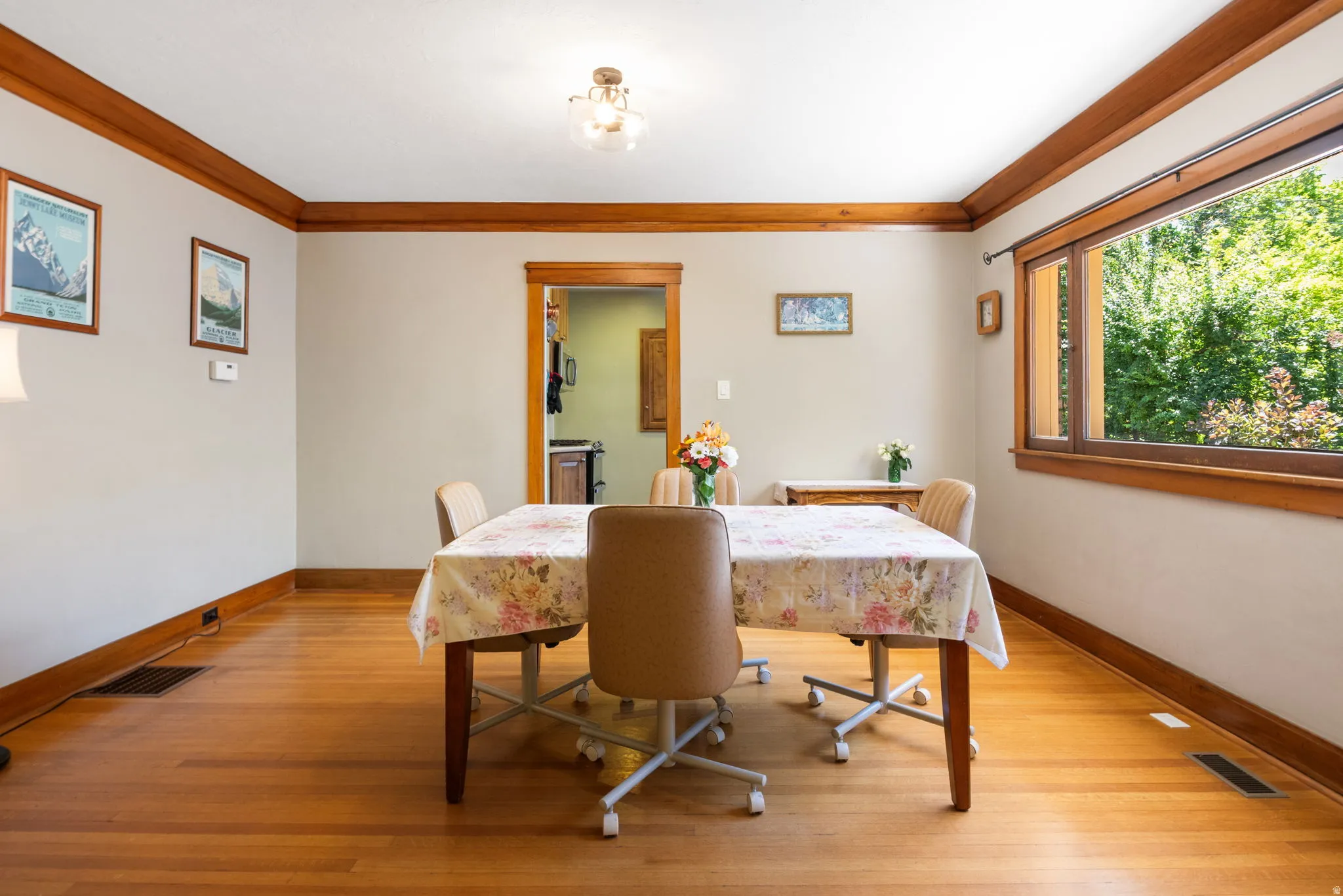 Hardwood flooring and rich wood trim enhance this room featuring a large picture window and a ceiling-mounted light fixture