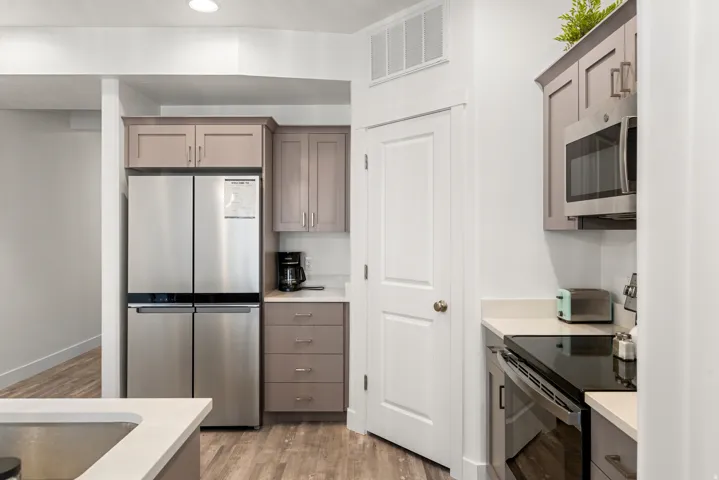 Kitchen featuring light gray cabinetry, stainless steel appliances, light-toned countertops, and wood-finish flooring