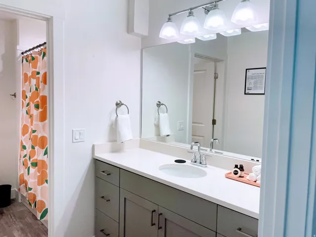 Bathroom vanity featuring a single basin sink, chrome faucet, and expansive countertop
