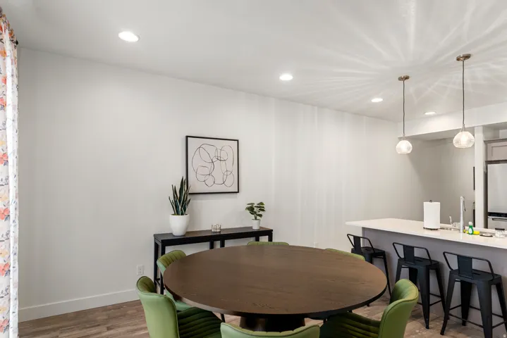 Open-concept dining area featuring wood-finish flooring, recessed lighting, and a kitchen island with pendant lights