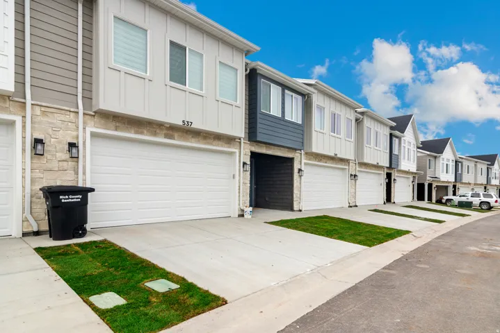 Modern townhome facades featuring varied siding, stone accents, and attached garages