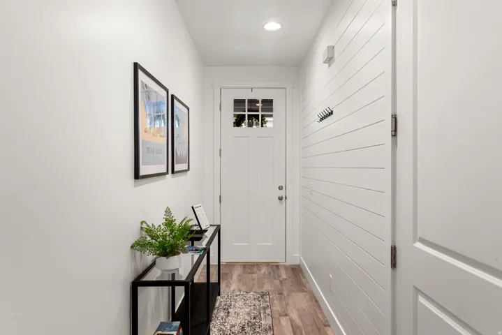 Entryway featuring a white paneled door with windowpanes, wood-finish flooring, recessed lighting, and a horizontal shiplap accent wall with coat hooks