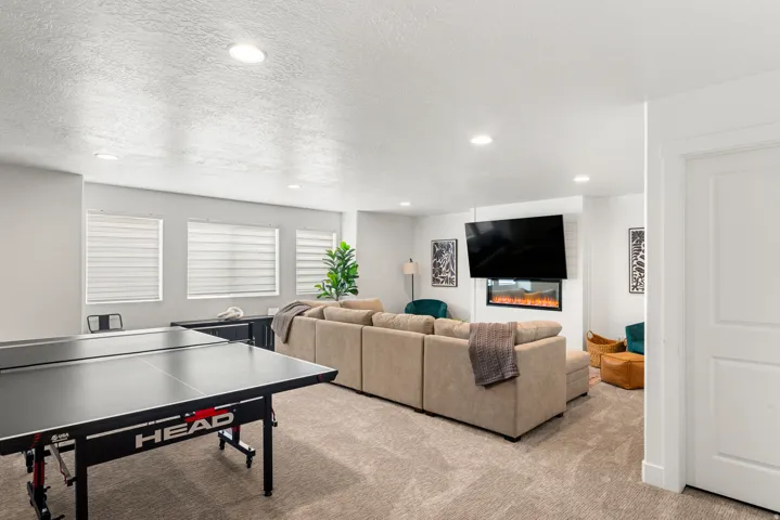 Spacious room featuring neutral carpeting, recessed lighting, and an integrated wall-mounted fireplace