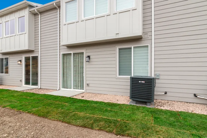 Rear elevation featuring horizontal siding, multiple sliding glass doors, and upper-level windows