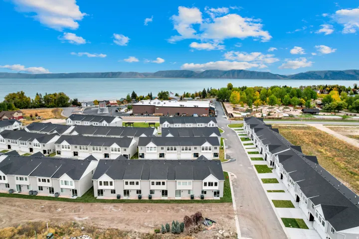 Aerial perspective showcasing a community of newly constructed multi-story townhomes with dark shingle roofs and light-colored siding