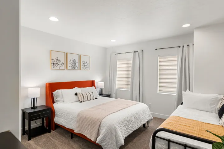 Spacious room featuring neutral carpeting, recessed lighting, white walls, and two windows with blinds and drapes