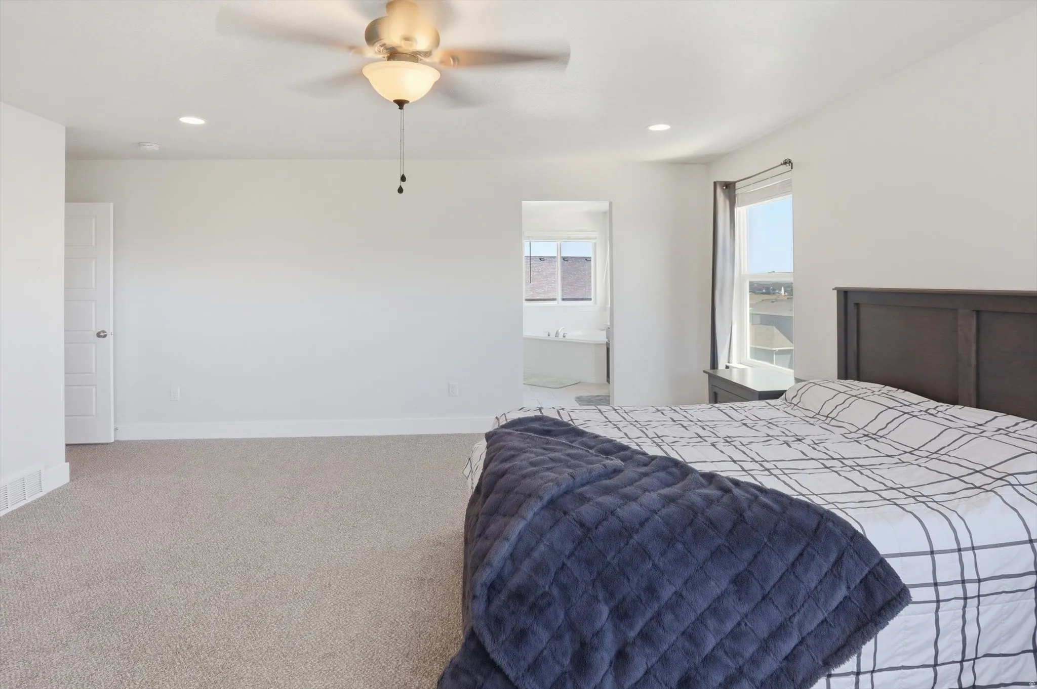 Spacious room featuring light-toned carpeting, ample wall space, and a ceiling fan with integrated lighting