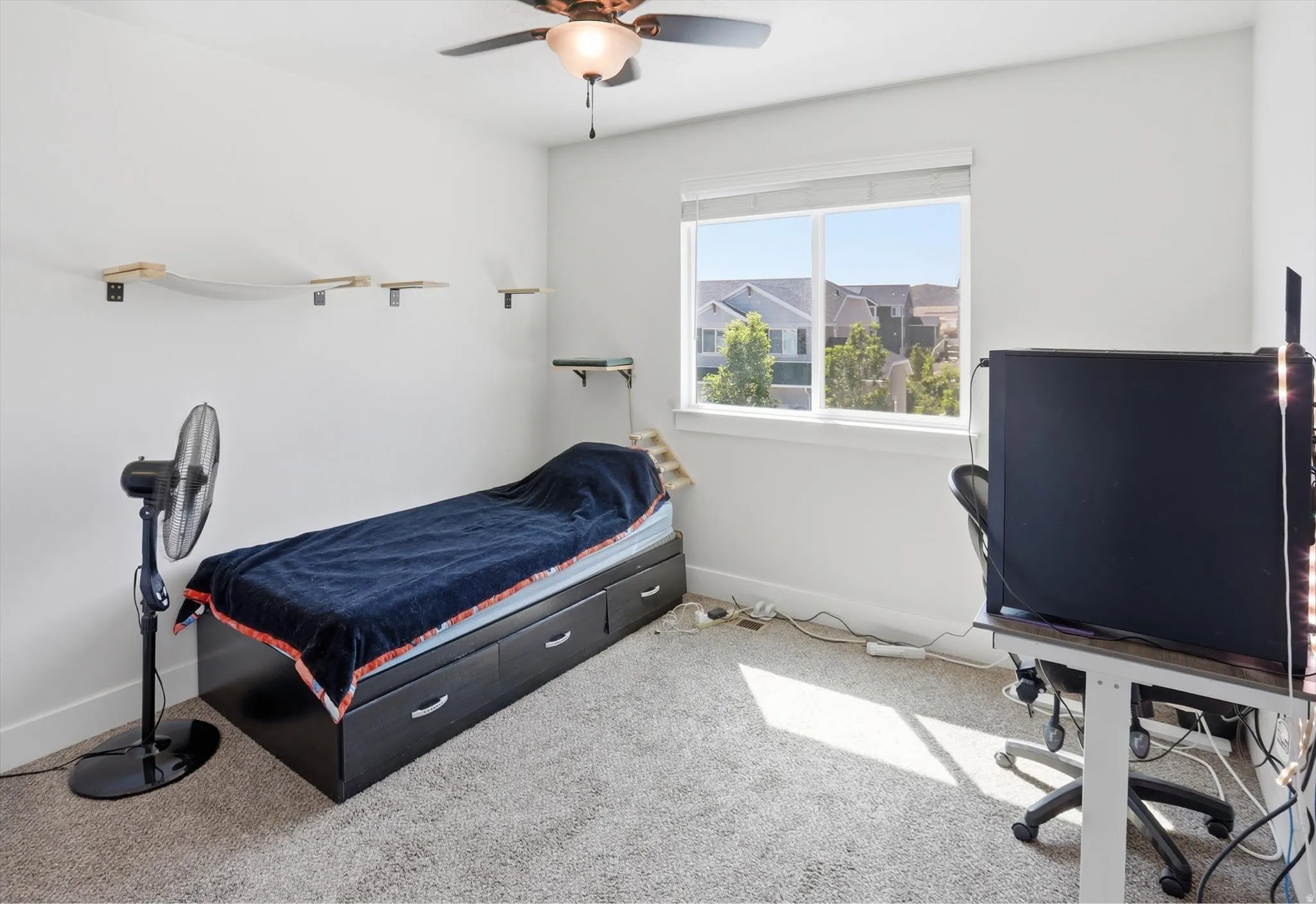 Bright room featuring a ceiling fan, a window with exterior views, and neutral-toned carpeting