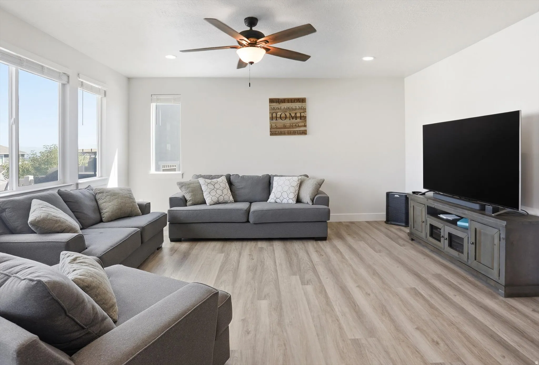 Open-concept living area featuring wood-finish flooring, recessed lighting, and large windows providing ample natural light