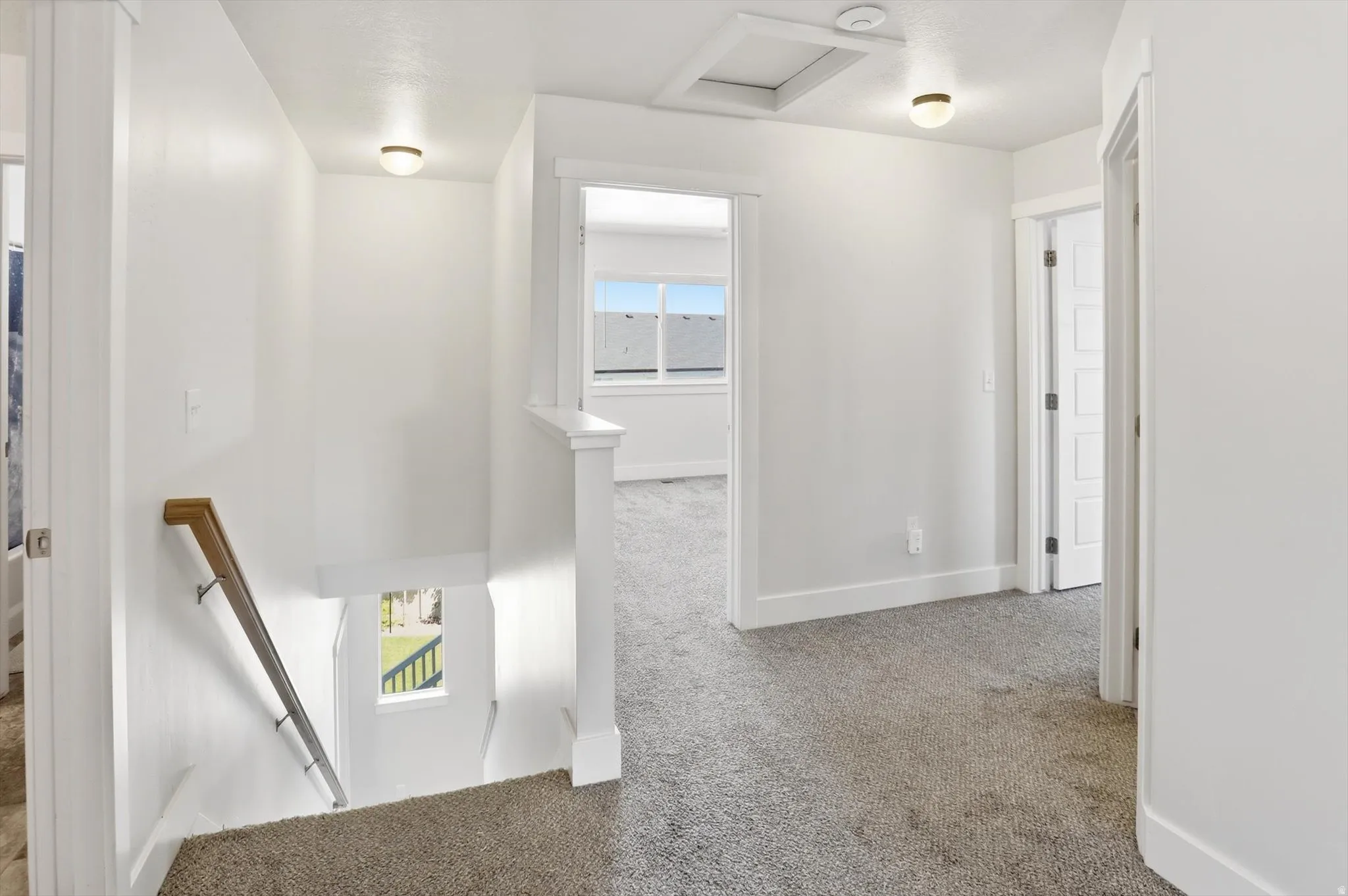 Upper-level hallway featuring a neutral gray carpet and bright white walls