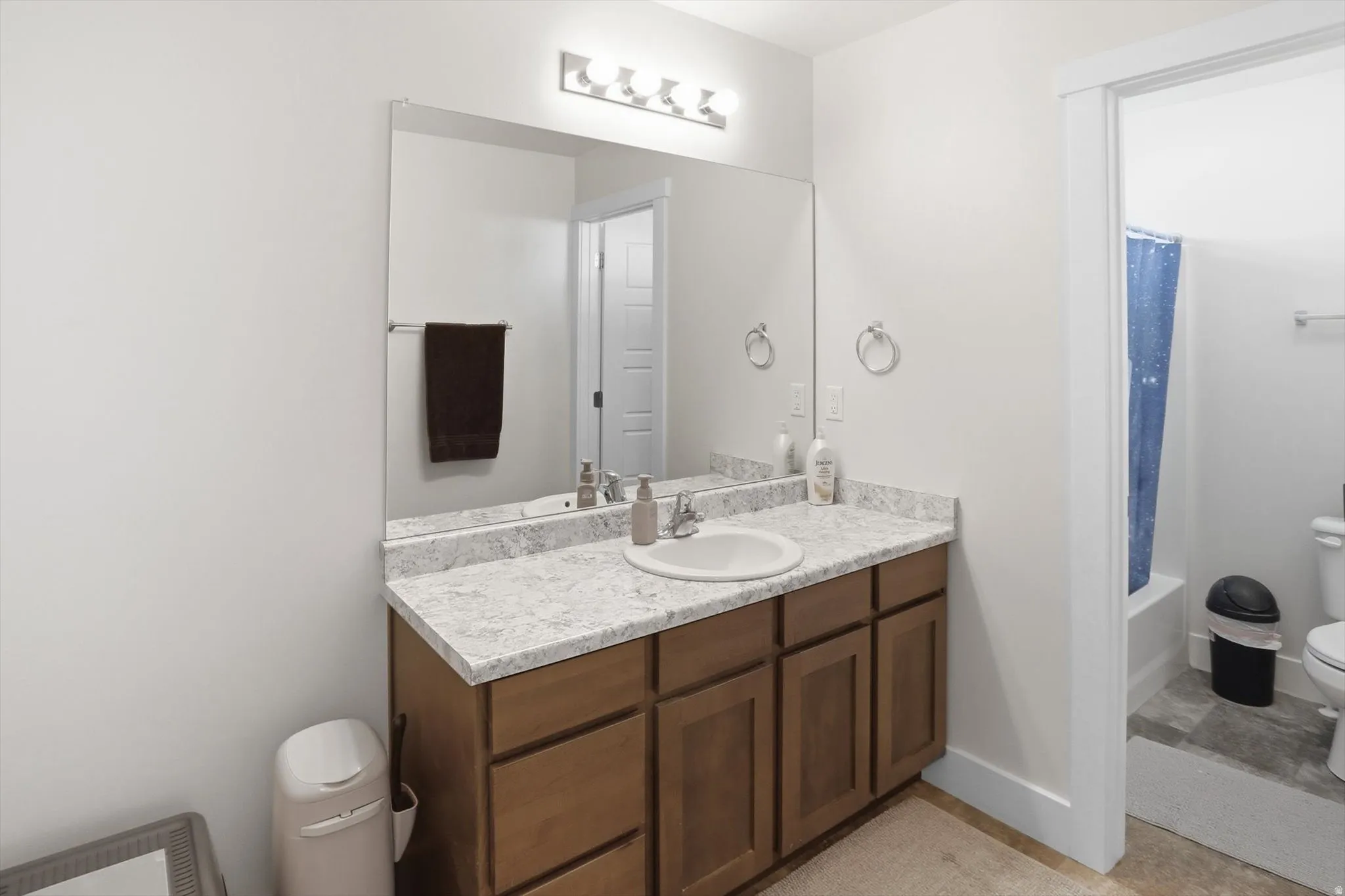 Bathroom vanity featuring a single basin, light-toned countertop, and wood-finish cabinetry