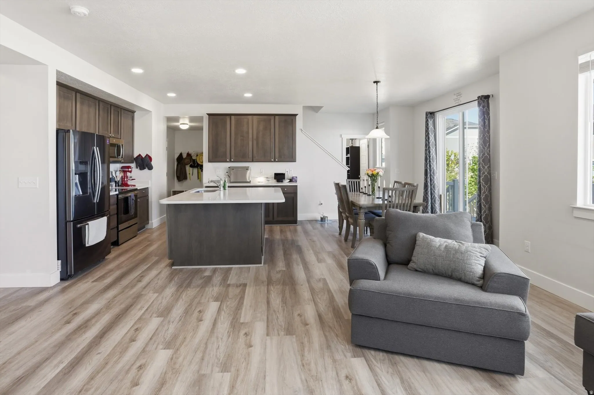 Open-concept living area featuring light wood-finish flooring, recessed lighting, and a neutral color palette