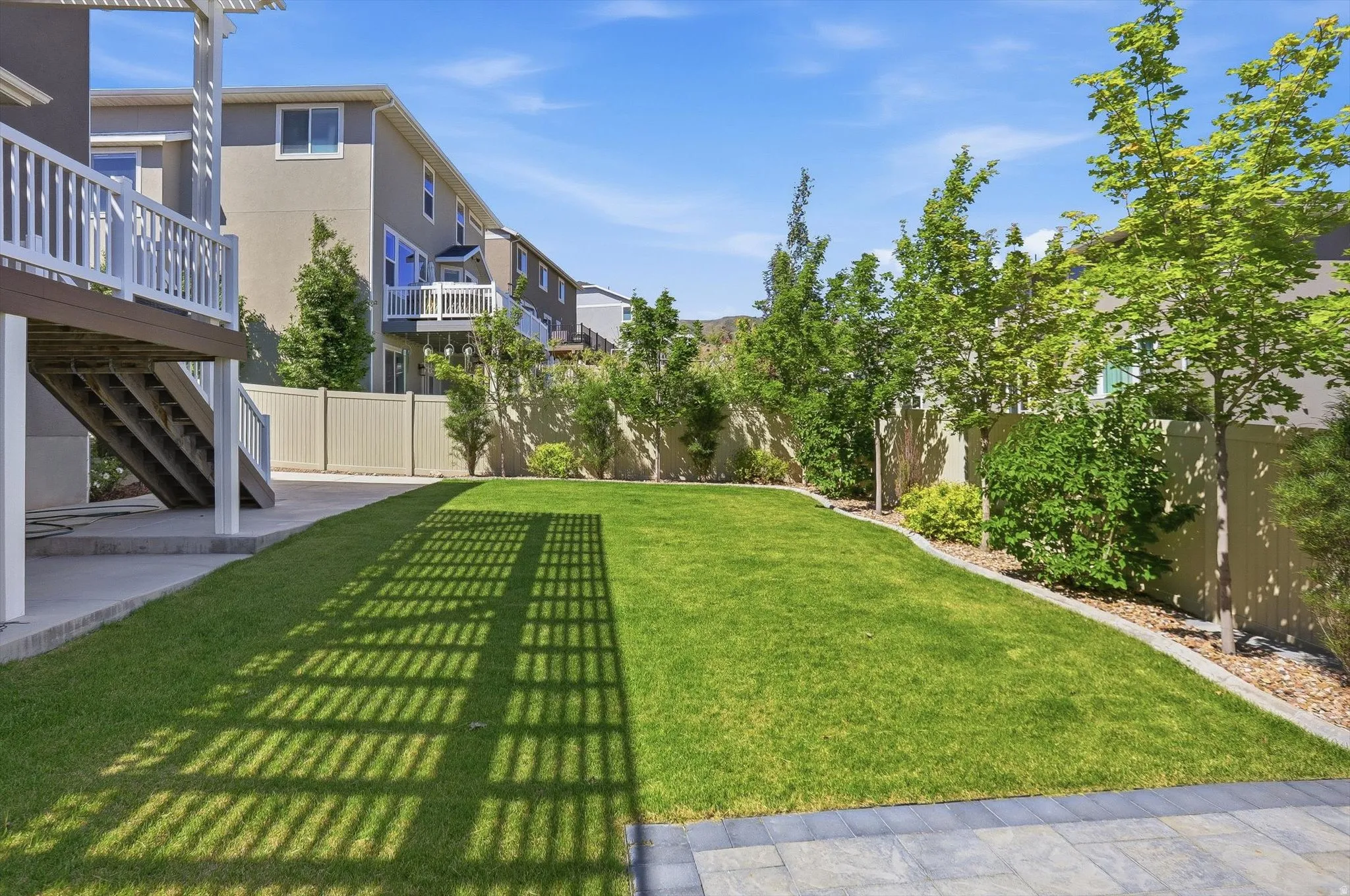 Expansive green lawn with mature trees and shrubs lining the perimeter