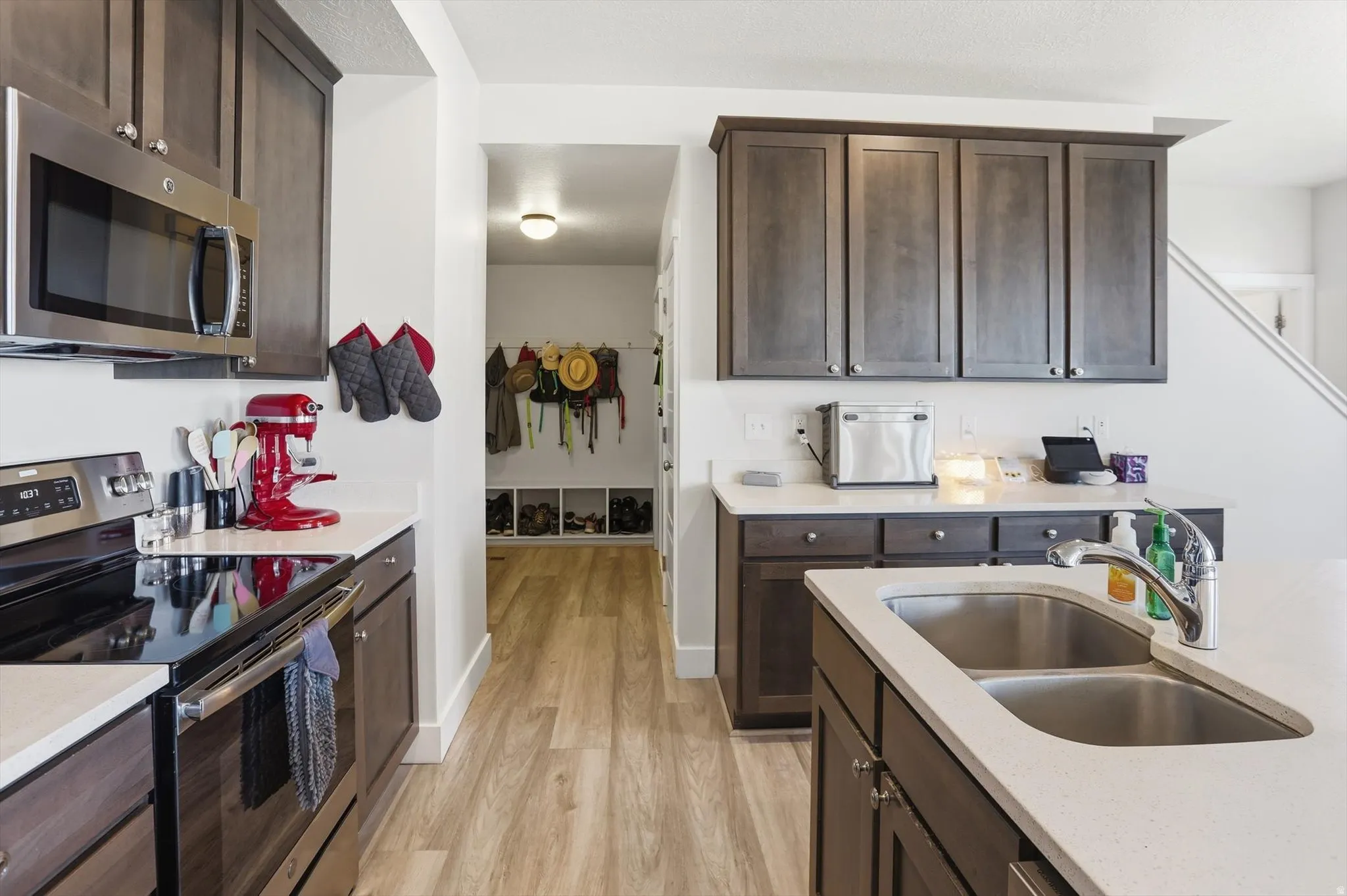Kitchen featuring dark wood-finish cabinetry, stainless steel appliances, and light-toned countertops